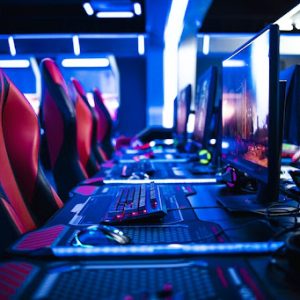 Game room interior with modern ambient lights and powerful super computers, consoles, keyboards for playing video games. Entertaining industry.